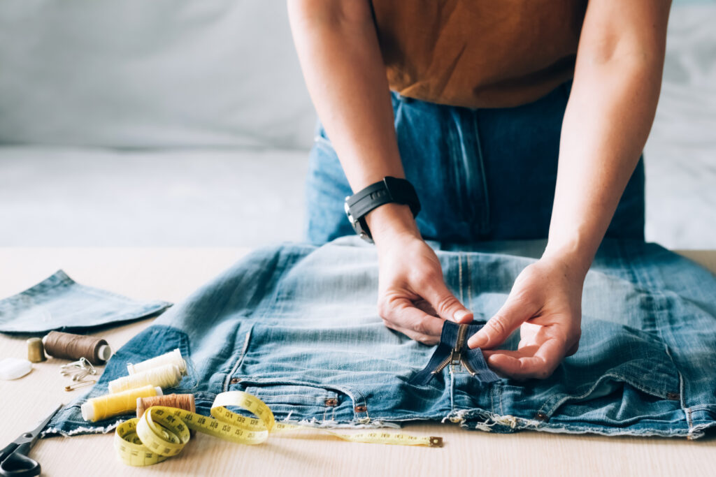 Woman repairs sews reuses fabric from old denim clothes economical reuse